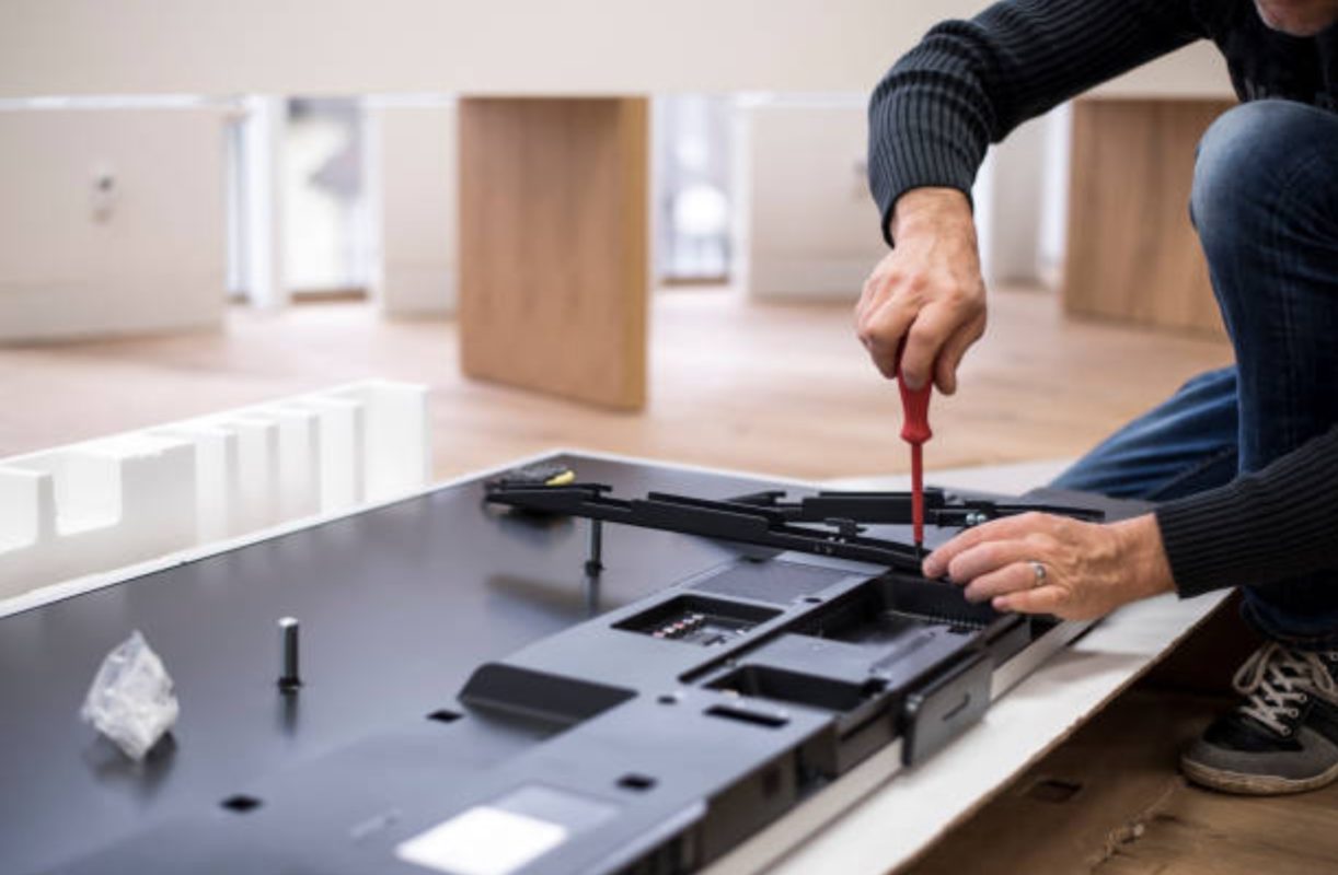 Technician installing rear brackets on to TV.